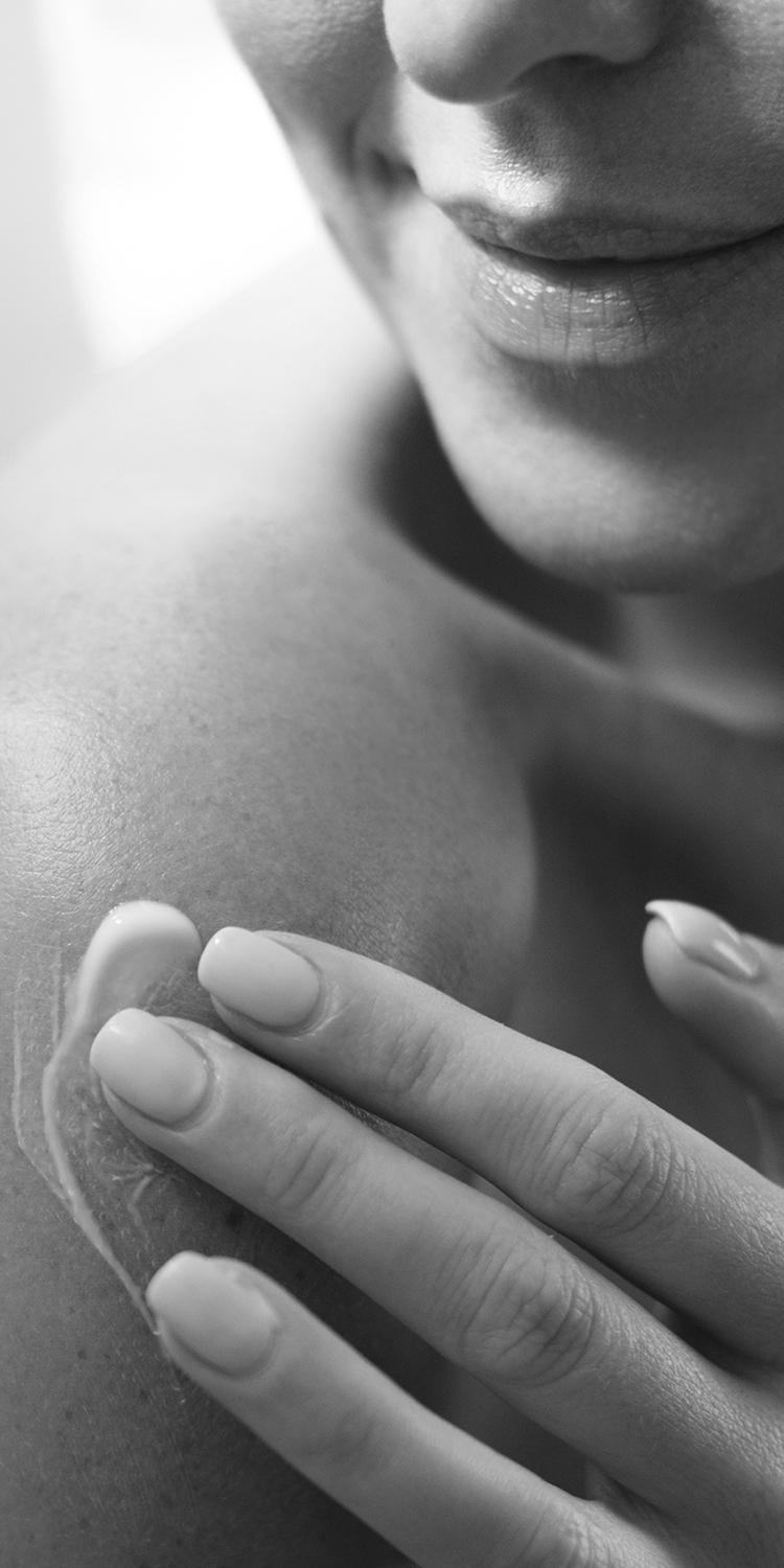Cropped Caucasian woman putting body lotion on her shoulder.